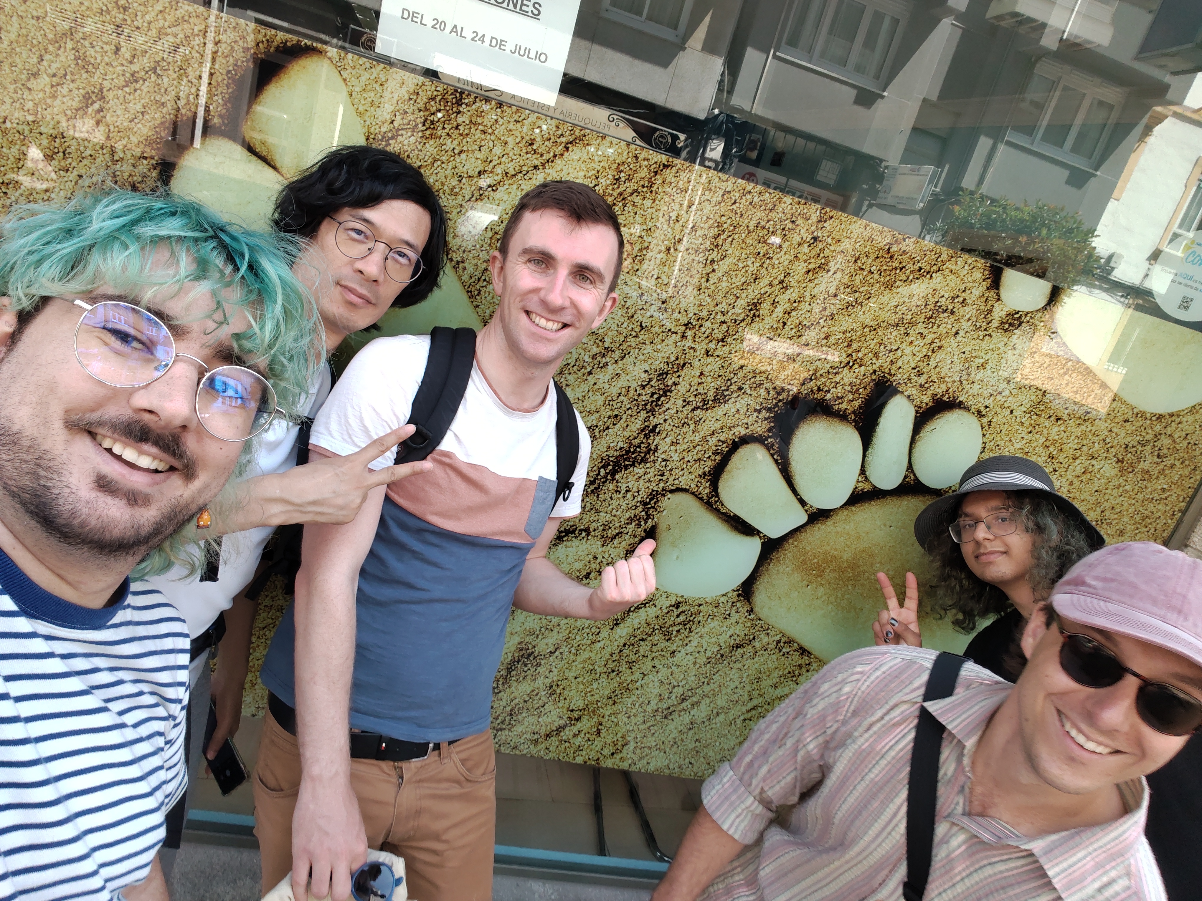 Philipp, myself, Guillaume, Charles and Tau in front of a building with a very sandy foot that looks rather similar to the GNOME Logo!